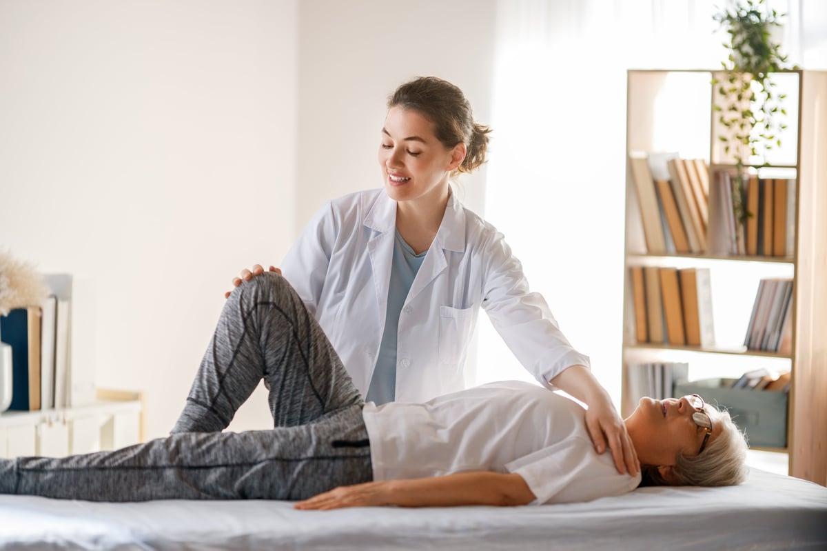 Fisioterapeuta ayudando a paciente mayor