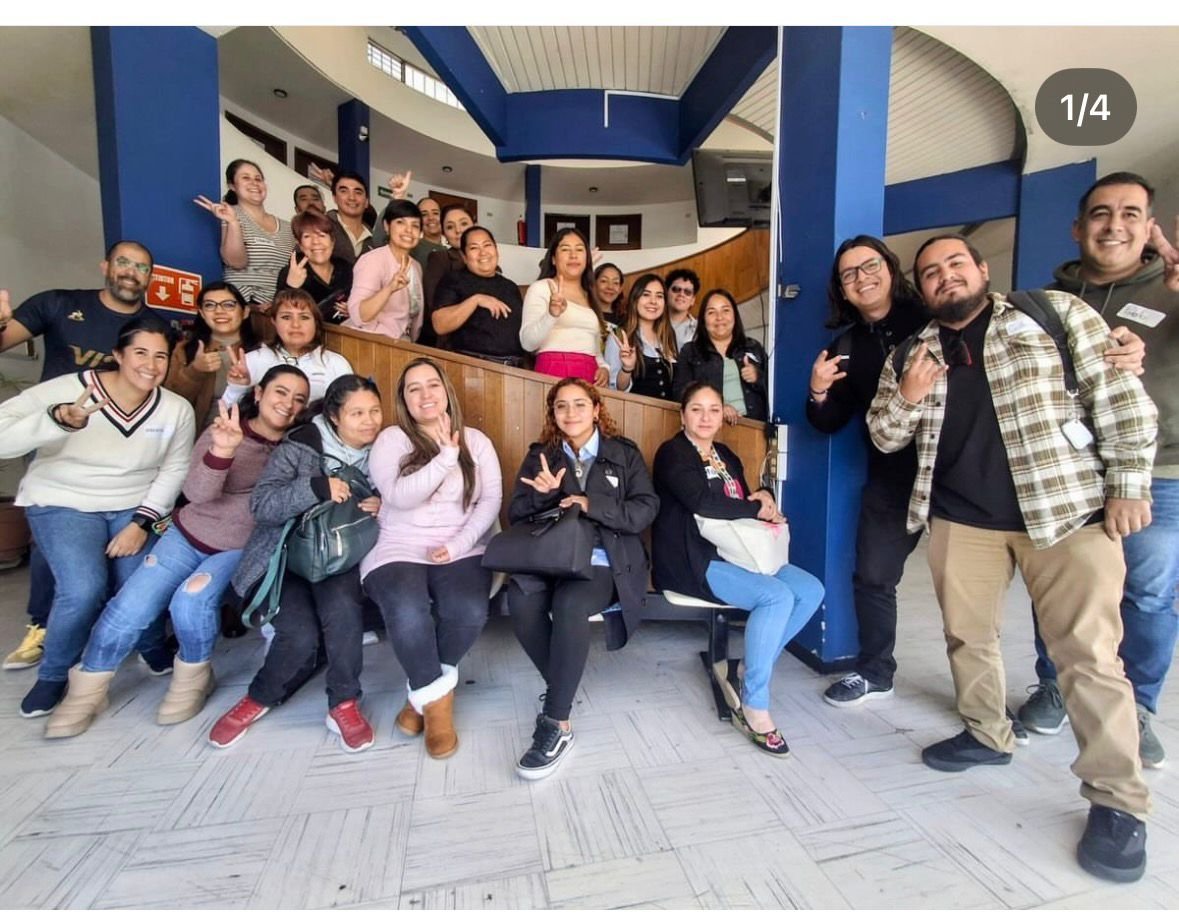 Large group of people posing together indoors in a modern office or community space with blue pillars and wooden accents