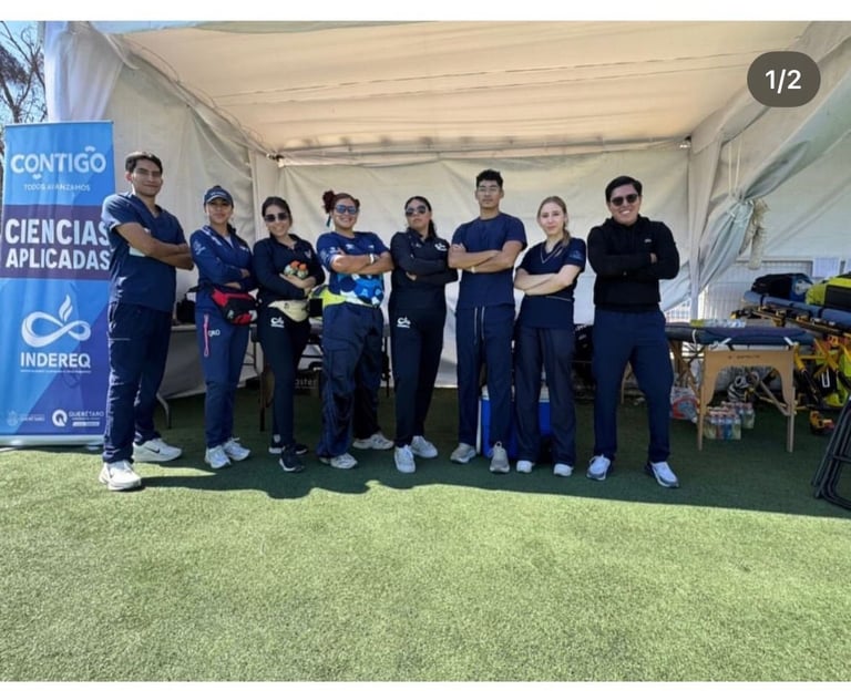 Group of people in blue uniforms standing together on artificial grass under a tent with a Contigo Ciencias Aplicadas Indereo banner visible
